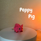 A pink pig keychain with red accents. The pig has a detailed design and is attached to a silver-colored keyring. The text "Peppy Pig" is displayed above the pig.