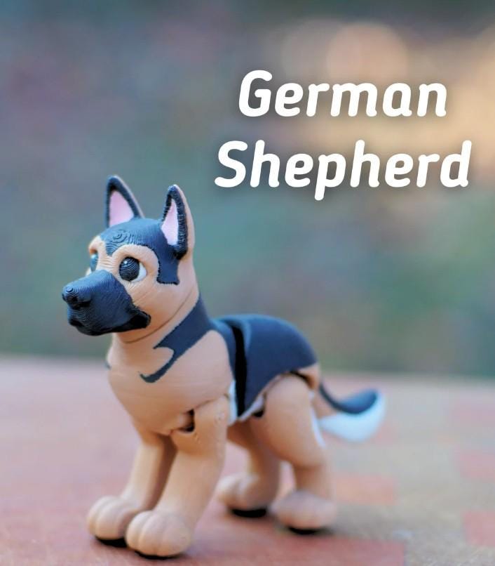 A small, articulated German Shepherd figurine featuring a tan and black color scheme with a textured surface. The dog has pointed ears, dark eyes, and a black muzzle. The text "German Shepherd" is displayed in white above the figure.